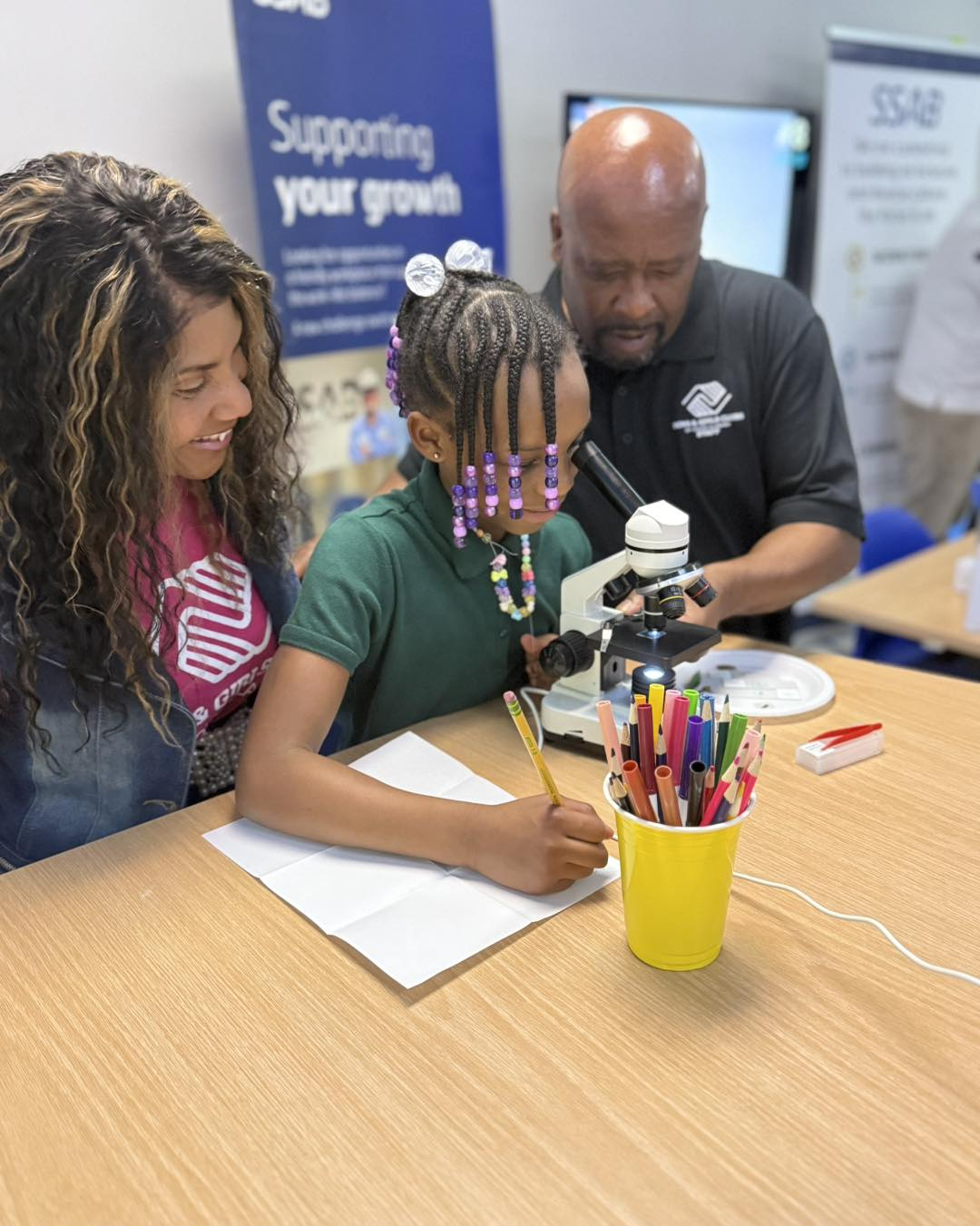 Club member looking through a microscope with caring mentors